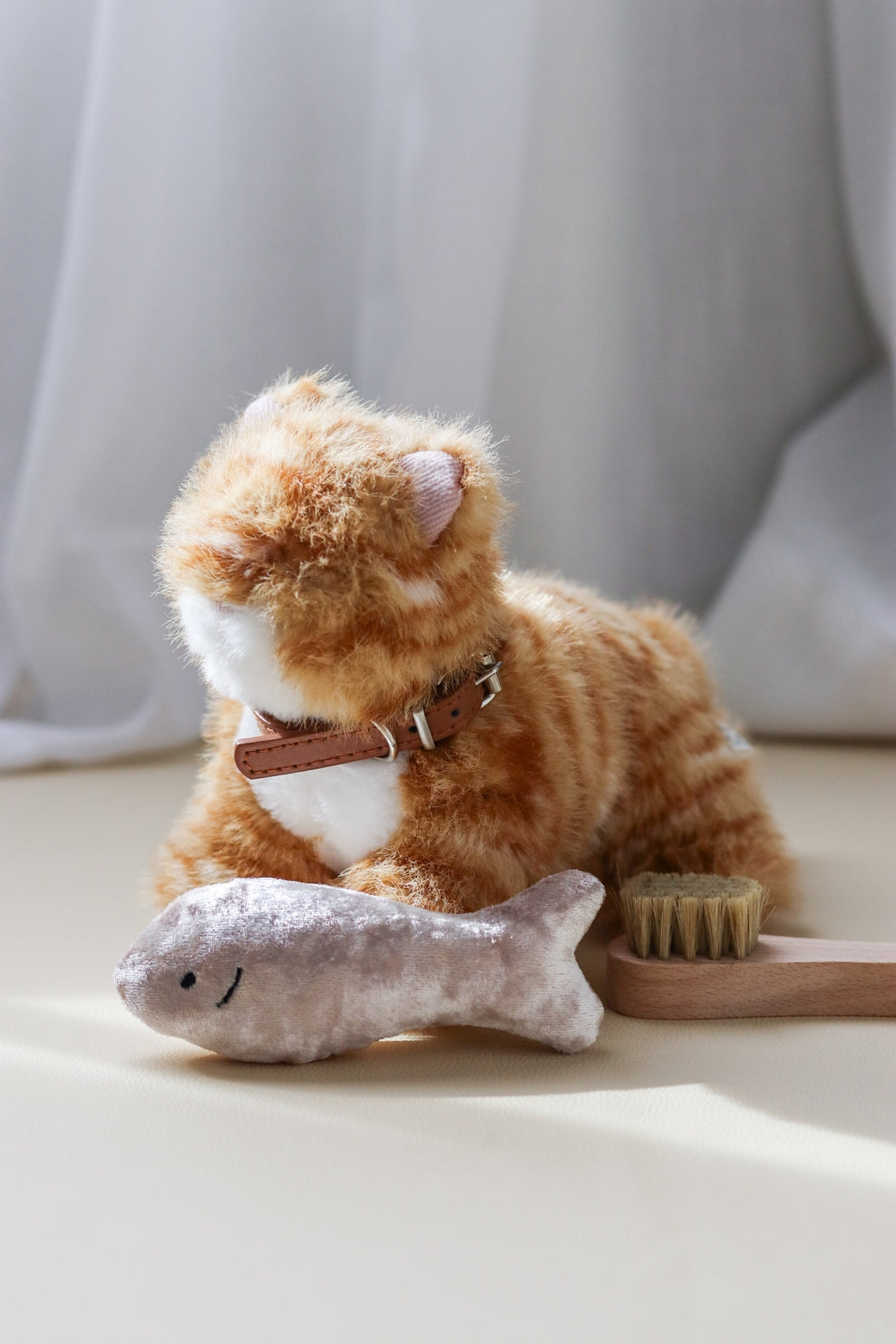 Plush cat toy with grooming tools on a light surface