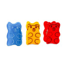 Three gummy bear-shaped items in blue, yellow, and red on a white background