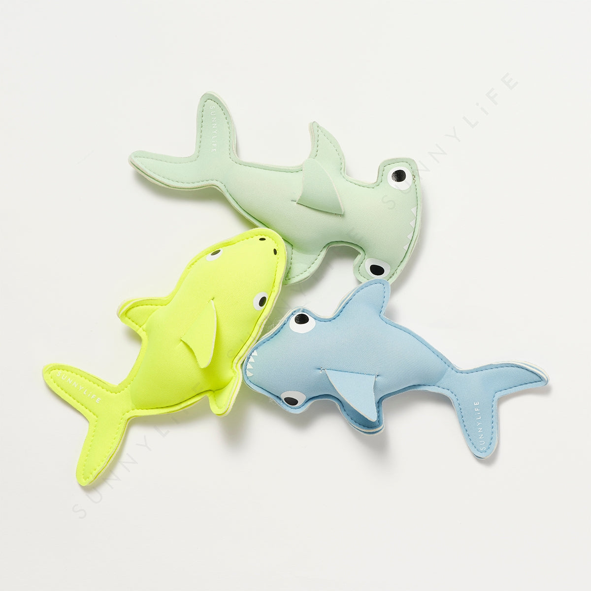 Three shark-shaped toys in green, yellow, and blue on a white background