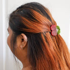 Person with orange and black hair wearing a decorative hair clip against a white background