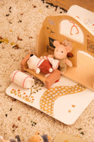 Toy pig and rabbit in a wooden toy house on a textured surface