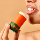 Person holding a 'kale me' lip balm against a beige background