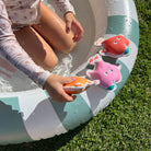 Child playing with colorful animal toys on a inflatable pool ring outdoors.
