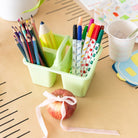 Green pencil holder with stationery items on a desk