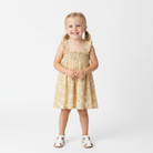 Young girl wearing a yellow floral dress on a white background
