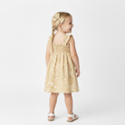 Young girl wearing a gold dress with a bow on a white background