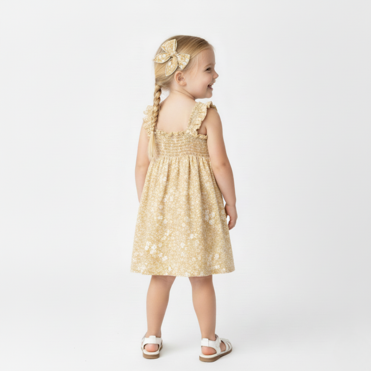 Young girl wearing a gold dress with a bow on a white background