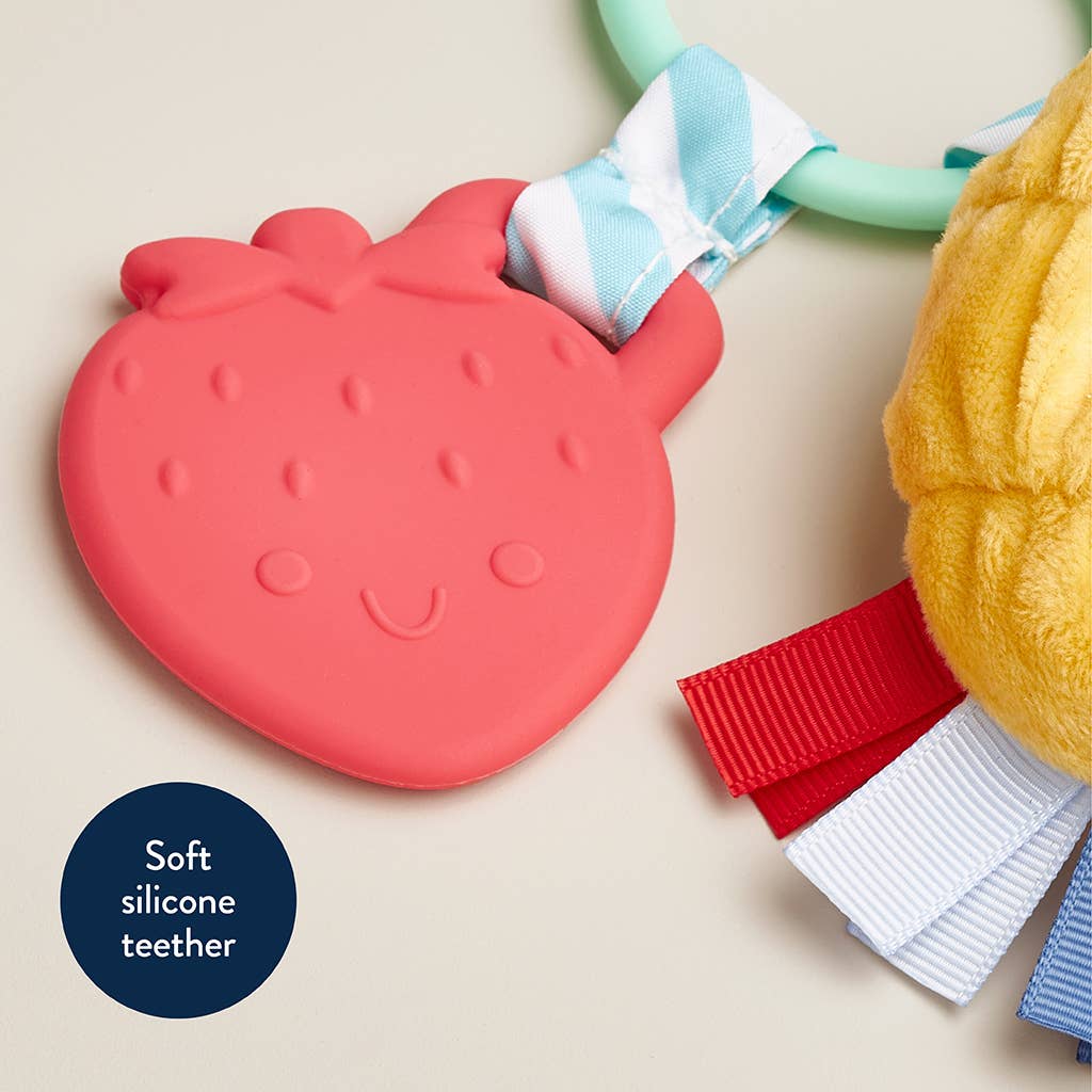 Red silicone teether with a strawberry design on a beige background