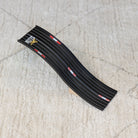Black plastic strip with red and white accents on a beige carpet