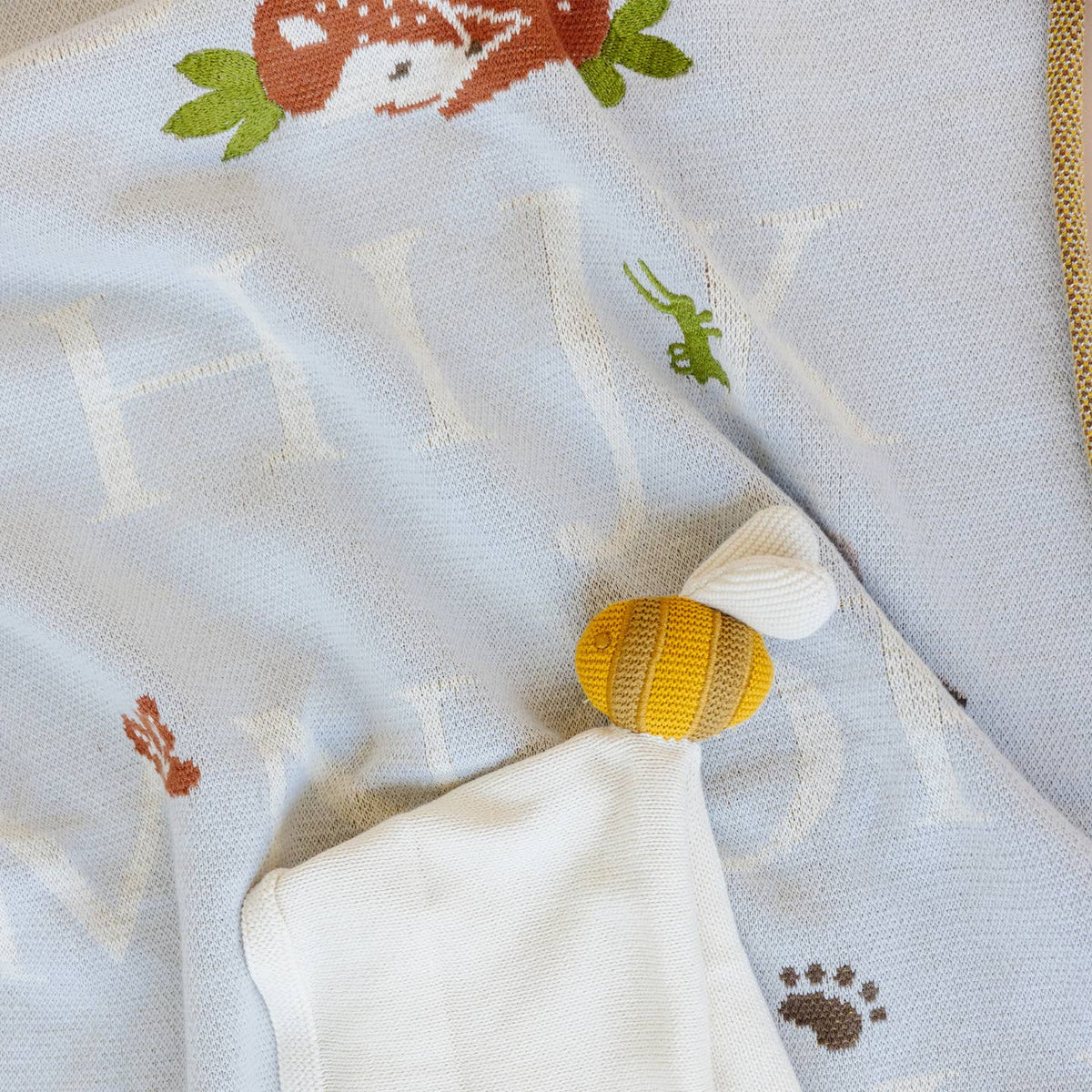 Close-up of a baby's rattle toy on a textured blanket with animal prints