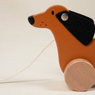 Wooden toy dog with a black bow tie on a beige background