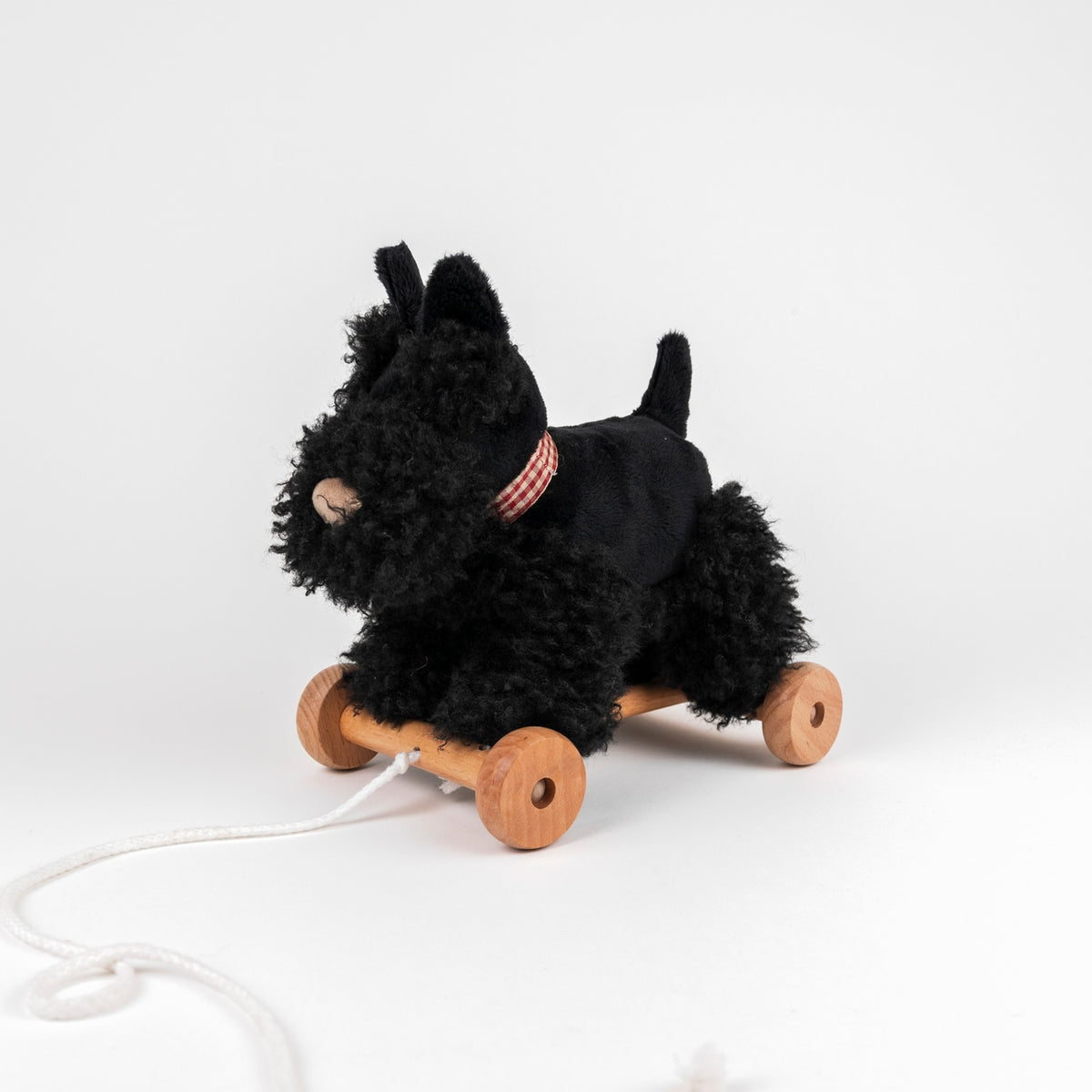 Black plush toy on wheels with a white background