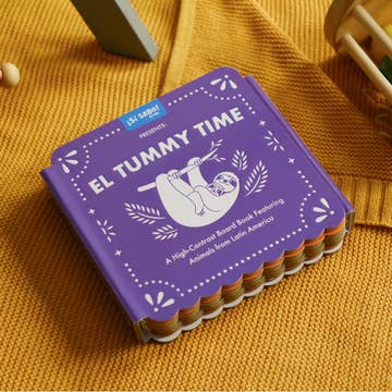 Purple book titled 'El Tummy Time' on a yellow textured surface