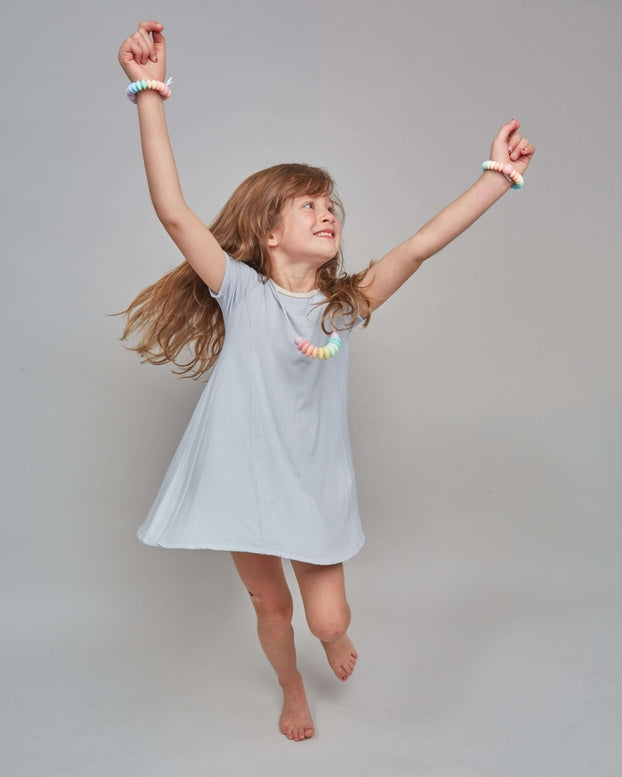 Young girl in a light blue dress posing against a plain background