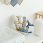 Nursery with baby clothes, a plush toy, and a basket on a white surface.