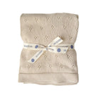 Folded beige blanket with a white ribbon and 'The Blueberry Hill' label on a white background