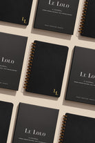Black journals with 'Le Lolo' branding on a light beige background