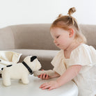 Child playing with a plush toy dog on a light-colored surface.