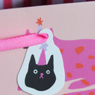 Illustration of a black cat wearing a party hat on a pink background