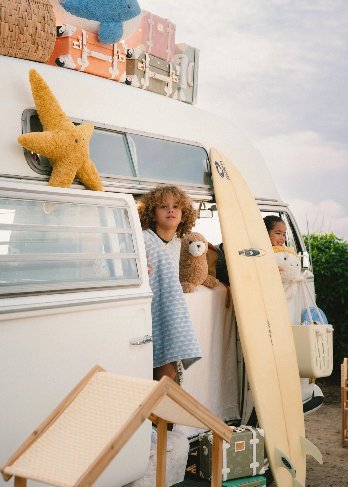 Children with a surfboard and toys near a van