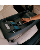 Hand reaching into a car's central console tray with a beige interior.