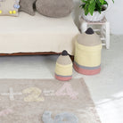 Two woven stools in a child's room with a rug featuring numbers and letters.