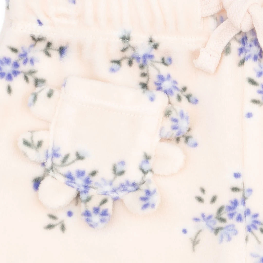 Close-up of a soft cream-colored fleece garment with a small decorative pocket and blue floral embroidery.