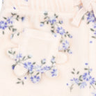 Close-up of a soft cream-colored fleece garment with a small decorative pocket and blue floral embroidery.