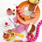 Colorful ice cream-themed playset with a 'Sundae' plate, ice cream cones, and accessories on a white background.