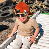Child wearing a red cap and sunglasses on a wooden bench with a natural background