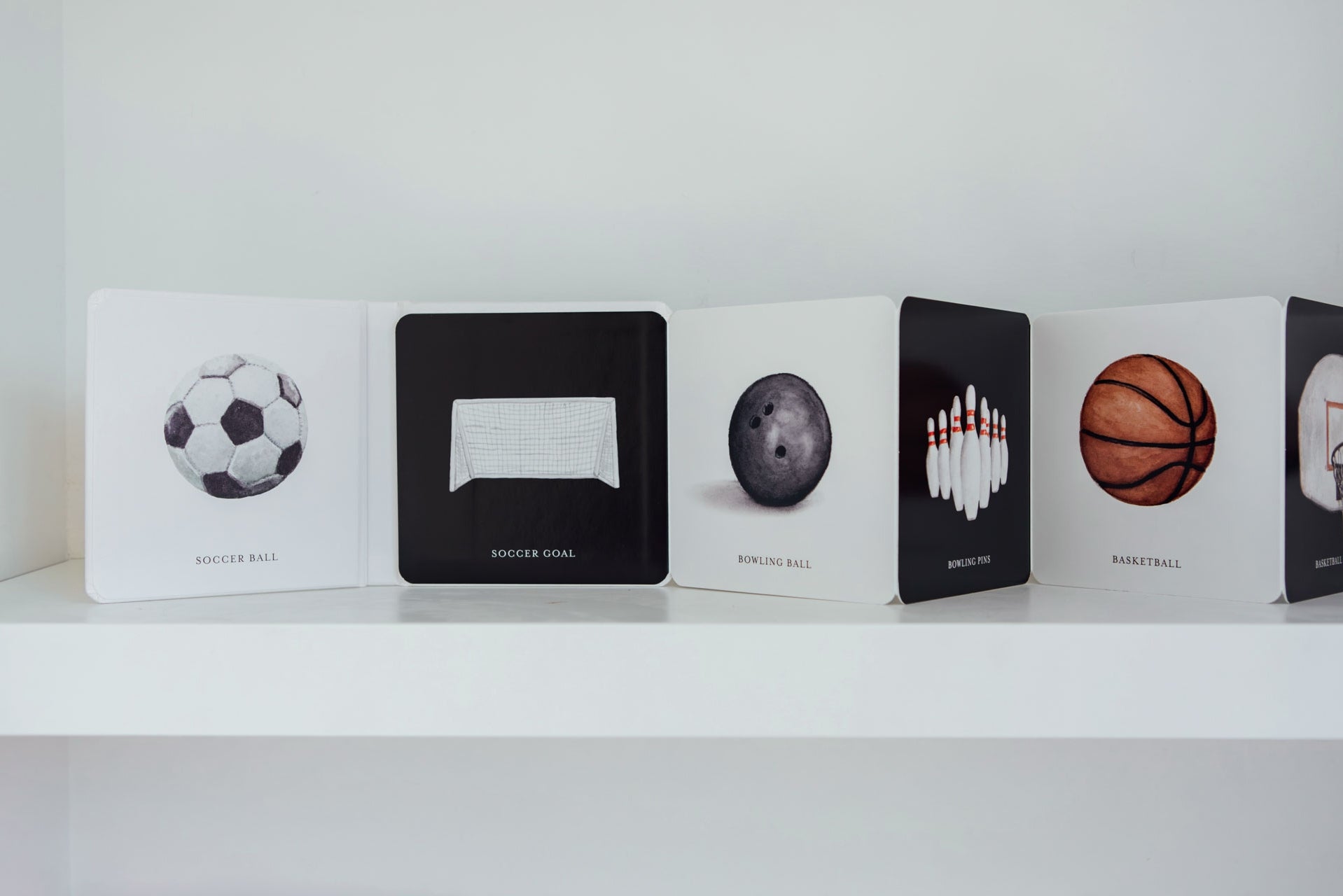Collection of card decks with sports-themed designs on a white shelf.