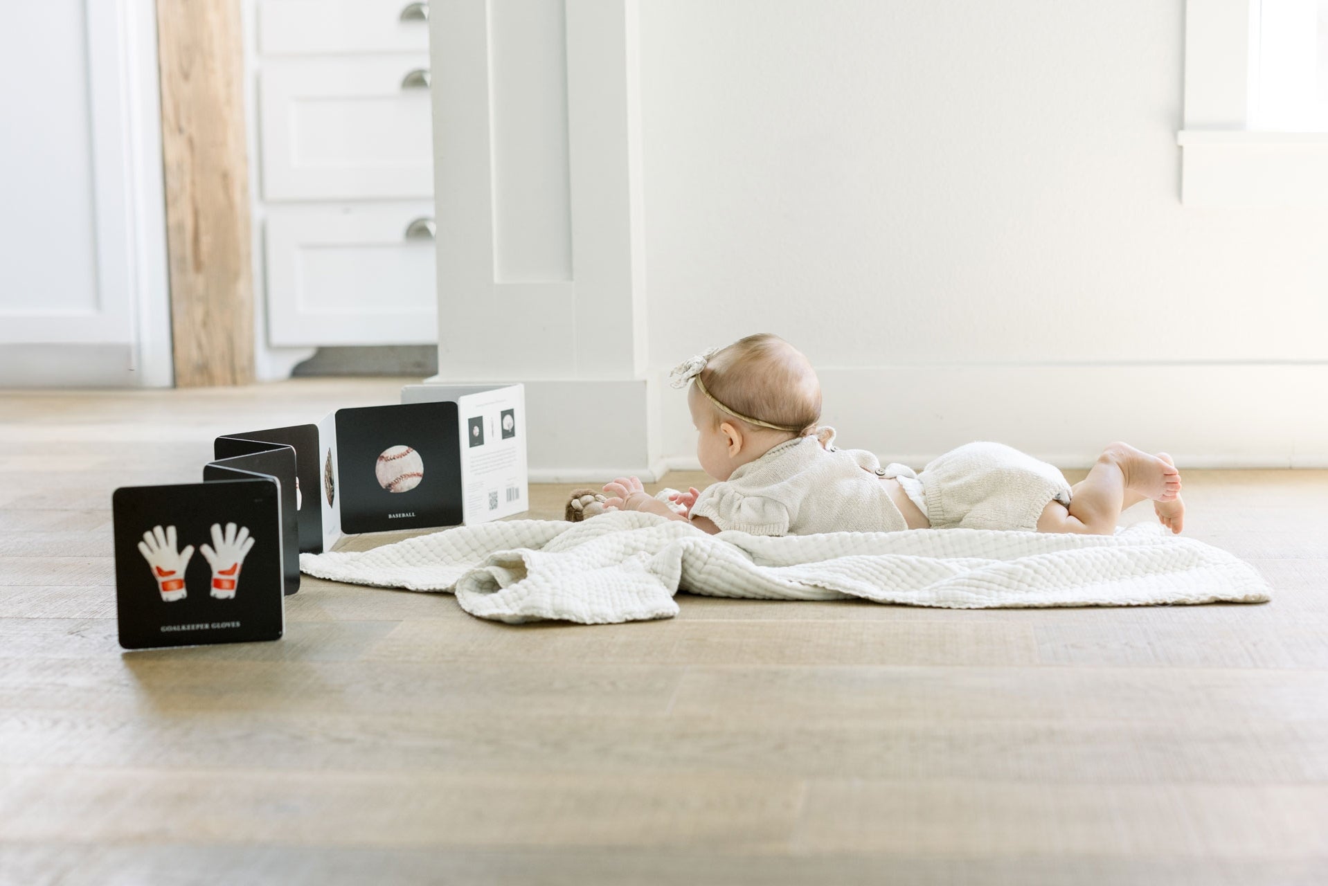 Baby lying on a blanket with educational cards on a wooden floor