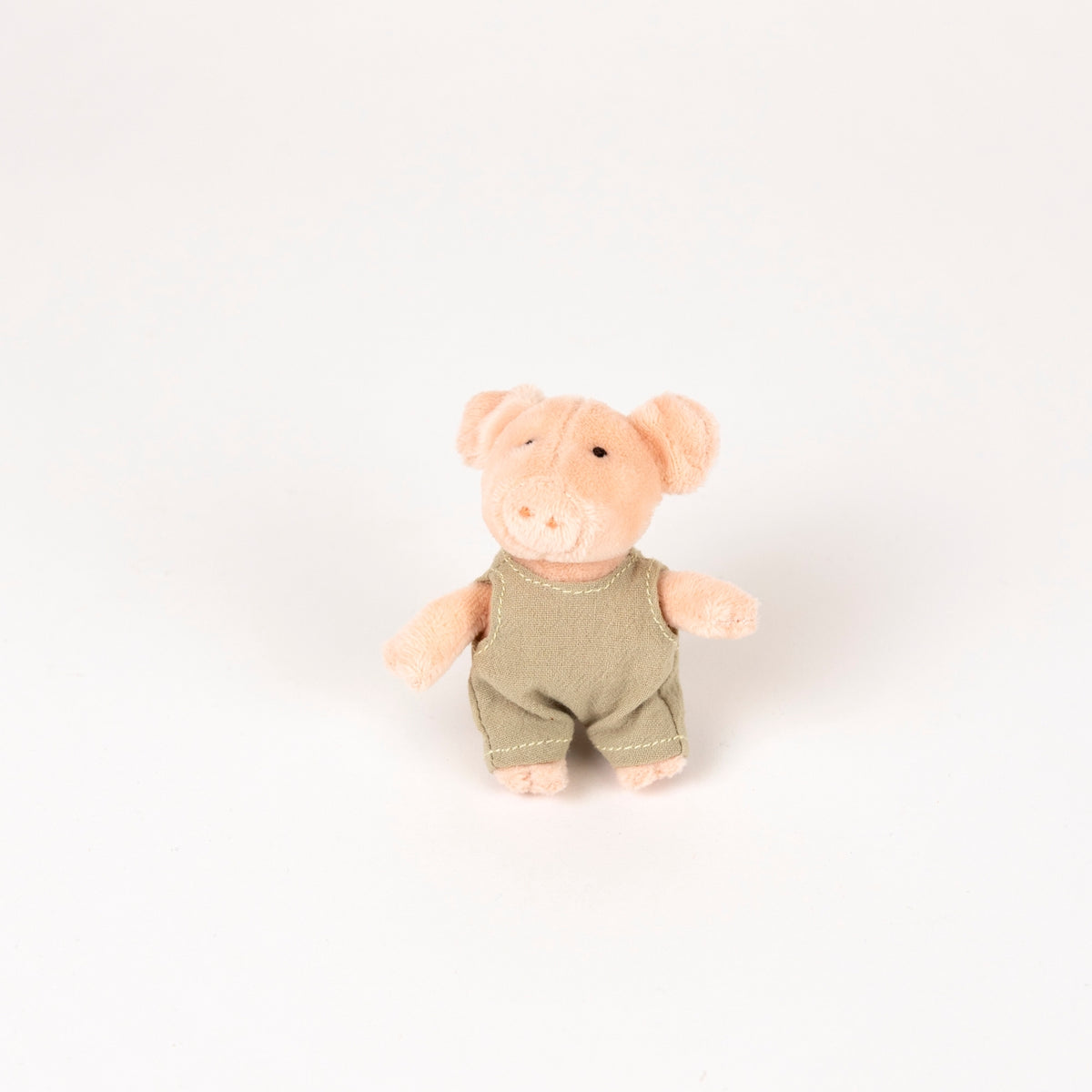 plush pink pig with beige romper - view from the front  further back on a white background