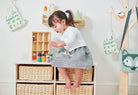 Child playing with toys in a room with wooden shelves and decor.