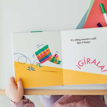 Child holding a colorful book with illustrations and text