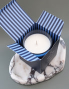 Candle in a striped box on a marble coaster