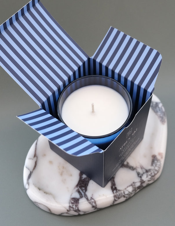 Candle in a striped box on a marble coaster