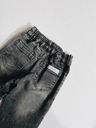 Black denim jeans with a brand label on a white background
