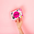 Coloring book held by hand on pink background