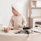 Child playing with toys on a light-colored surface in a minimalistic room.
