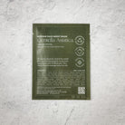 Korean face sheet mask packaging with green background on a textured gray surface
