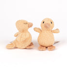 Two small plush duck toys in a warm beige/tan color, shown on a clean white background. One toy is facing away to show the back, and the other is facing forward to show the front.