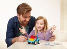 Man and young girl playing with a toy truck on a table.