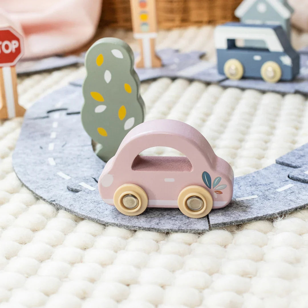 Pink toy car on a felt road with a stop sign and other toys in the background