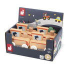 A retail display box of wooden Janod toy trains, featuring multiple natural wood trains with orange roofs and illustrated windows, set against a clean white background.