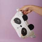 Panda-shaped pouch held by a hand against a purple background