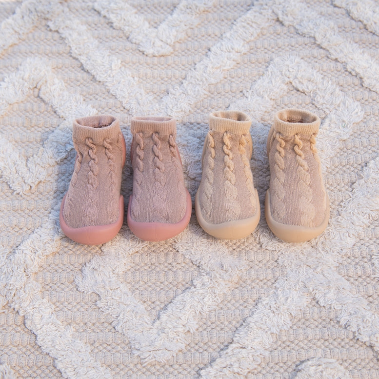 Four pairs of knit boots on a textured surface