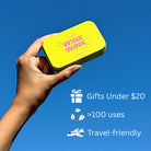 Hand holding a yellow 'Wink Wink' product against a blue sky with promotional text.