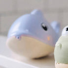 Two cartoonish shark toys on a white surface with a blurred background