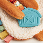 Plush toy with a teal house-shaped tag on a soft surface